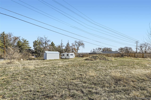 view of yard with a storage shed, an outdoor structure, and fence