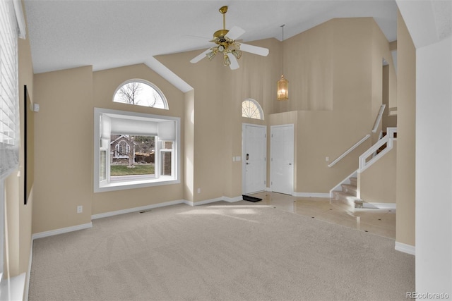 carpeted foyer with ceiling fan and high vaulted ceiling