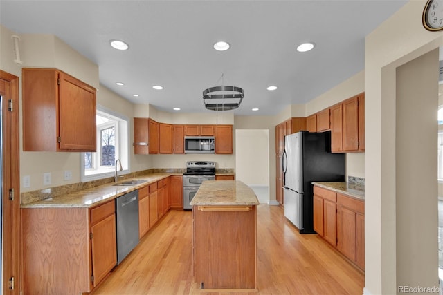 kitchen featuring sink, light hardwood / wood-style flooring, appliances with stainless steel finishes, light stone countertops, and a kitchen island