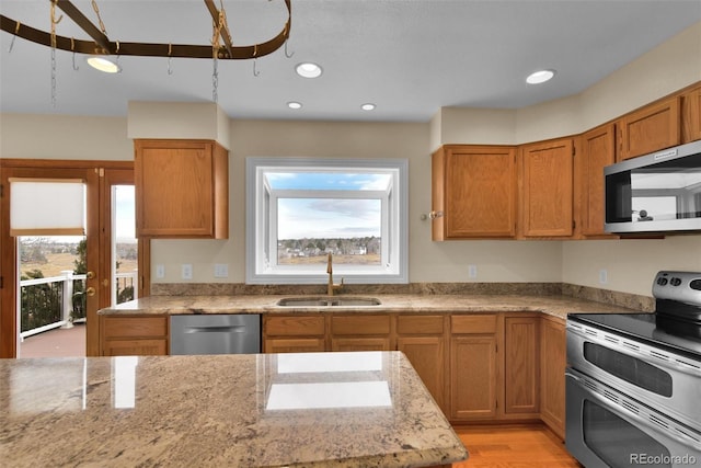 kitchen with light stone counters, a healthy amount of sunlight, appliances with stainless steel finishes, and sink