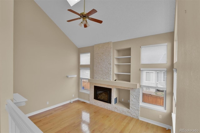 unfurnished living room featuring ceiling fan, hardwood / wood-style floors, built in features, and a fireplace