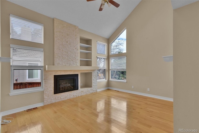 unfurnished living room with plenty of natural light, a fireplace, wood-type flooring, and built in features