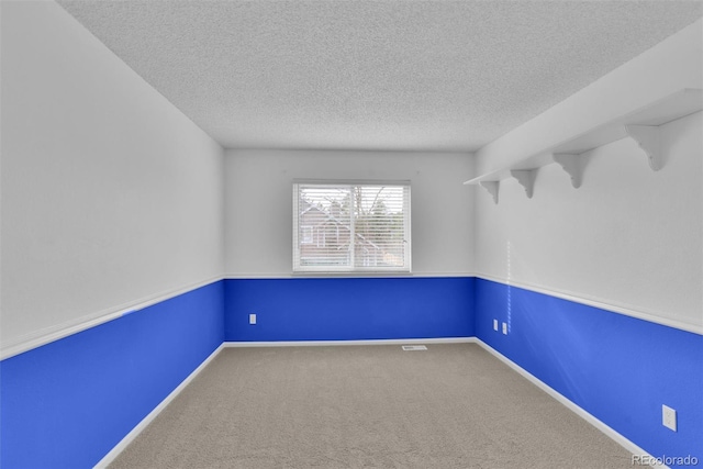 spare room featuring a textured ceiling and carpet flooring