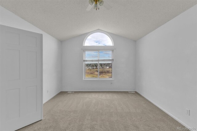 carpeted empty room with ceiling fan, lofted ceiling, and a textured ceiling