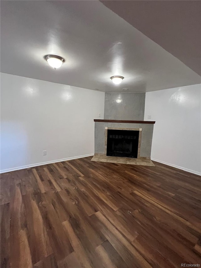 unfurnished living room with a large fireplace and dark wood-type flooring