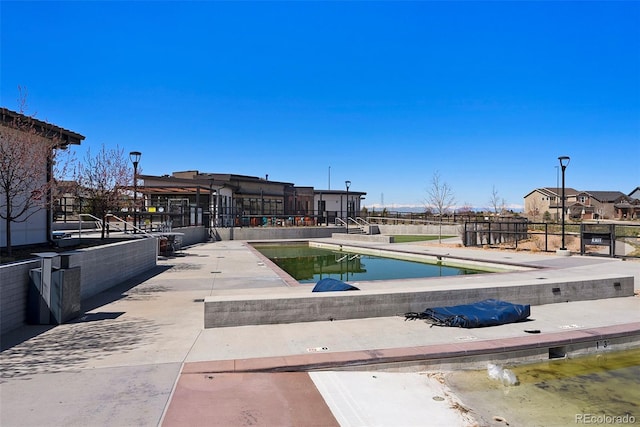 view of swimming pool featuring a patio and fence