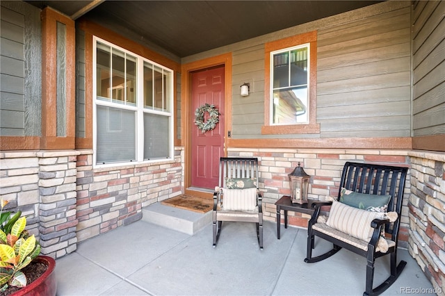 entrance to property featuring a porch and stone siding