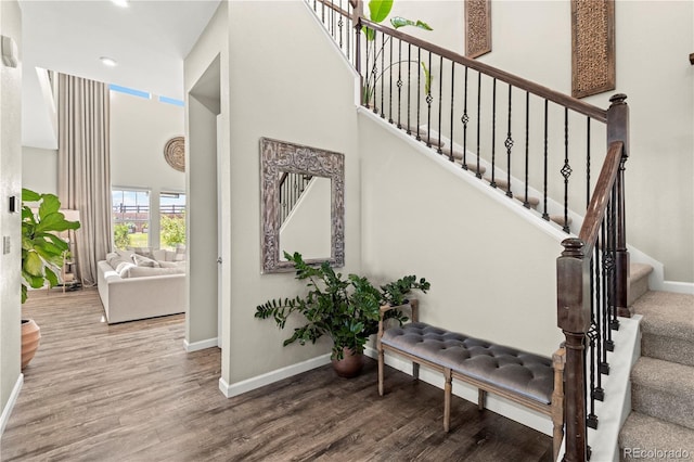 stairs with baseboards, recessed lighting, a towering ceiling, and wood finished floors