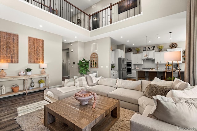 living area featuring dark wood-style flooring, recessed lighting, a high ceiling, and visible vents