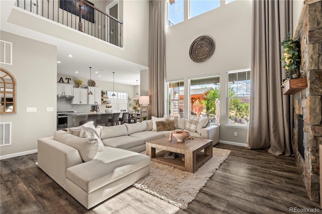 living room with dark wood-style flooring, baseboards, a healthy amount of sunlight, and a towering ceiling