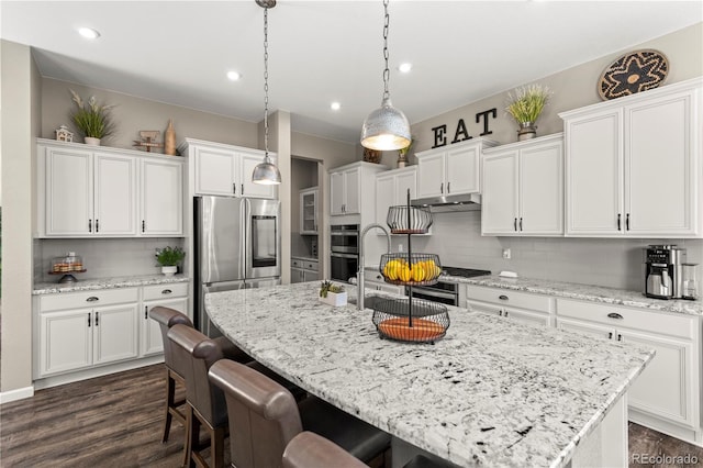 kitchen featuring an island with sink, decorative backsplash, appliances with stainless steel finishes, and white cabinets