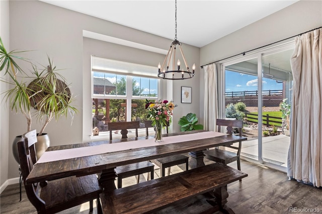 dining space with baseboards, a notable chandelier, and dark wood-type flooring