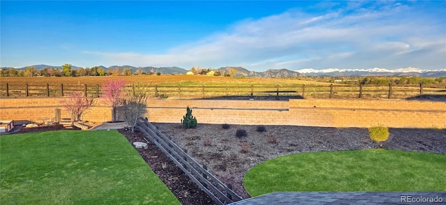 view of yard featuring a rural view, fence, and a mountain view