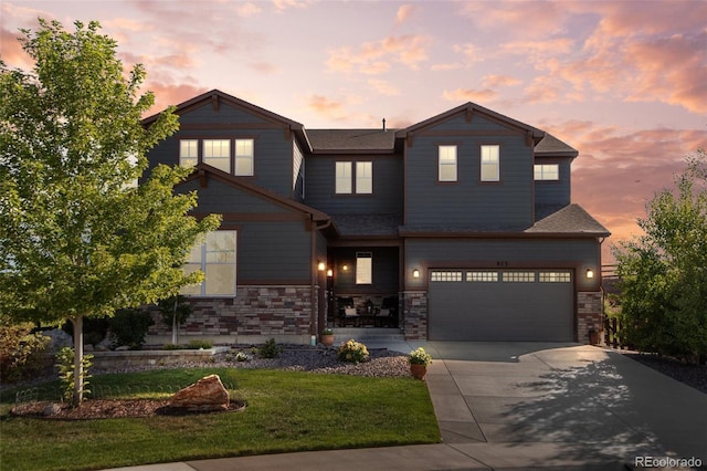 view of front of house with an attached garage, stone siding, driveway, and a front yard