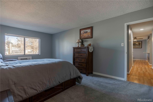 bedroom with a textured ceiling, light colored carpet, and baseboards