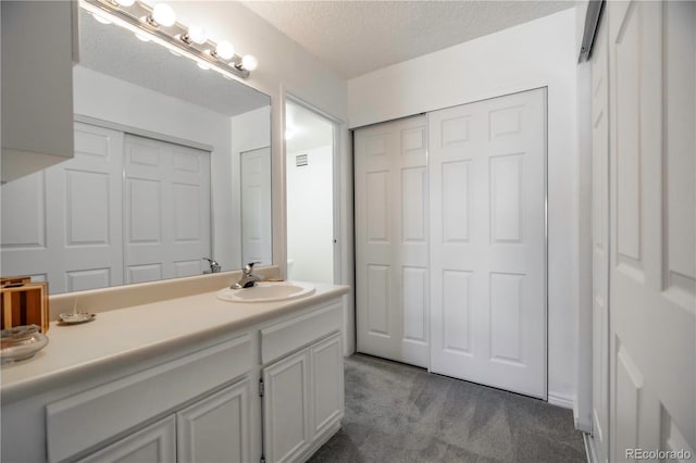 bathroom with a textured ceiling, a closet, and vanity