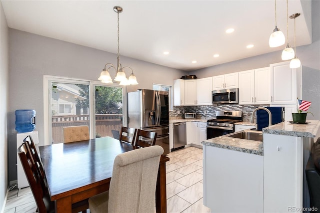 5033 Goshawk Ct, Brighton, CO 80601 - kitchen featuring stainless steel appliances, backsplash, a chandelier, white cabinets, and hanging light fixtures