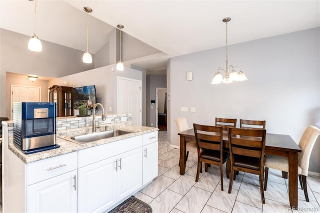 5033 Goshawk Ct, Brighton, CO 80601 - kitchen featuring a chandelier, white cabinets, tasteful backsplash, pendant lighting, and vaulted ceiling