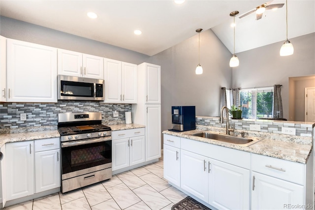 5033 Goshawk Ct, Brighton, CO 80601 - kitchen featuring appliances with stainless steel finishes, backsplash, white cabinets, vaulted ceiling, and hanging light fixtures