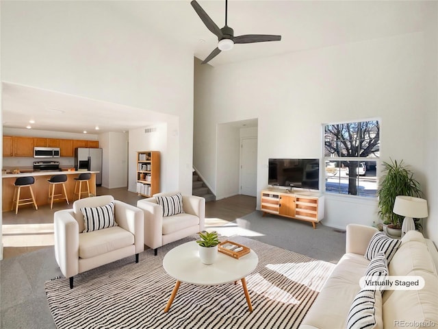 living room with ceiling fan and a towering ceiling