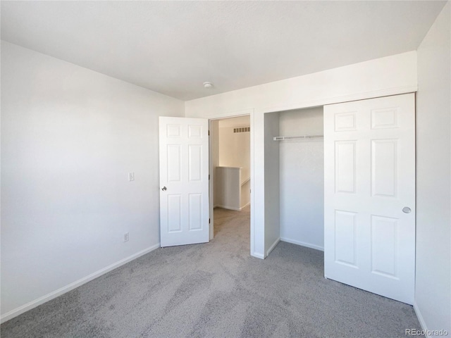 unfurnished bedroom featuring light carpet and a closet