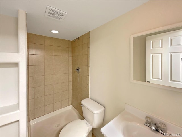 bathroom with tiled shower, toilet, and sink