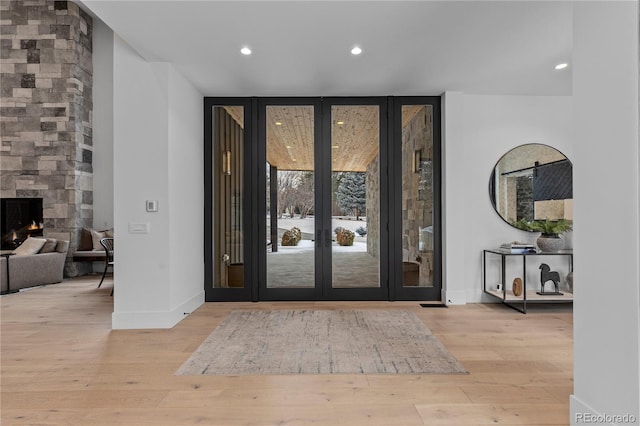 foyer entrance featuring a fireplace, floor to ceiling windows, wood finished floors, and baseboards