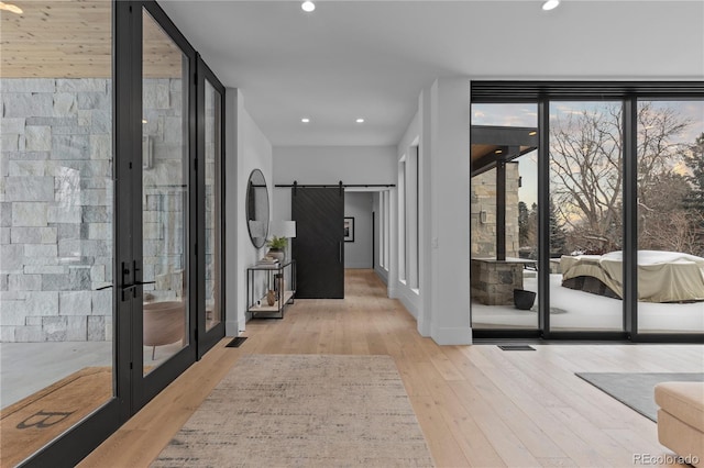 interior space featuring expansive windows, wood finished floors, recessed lighting, a barn door, and baseboards