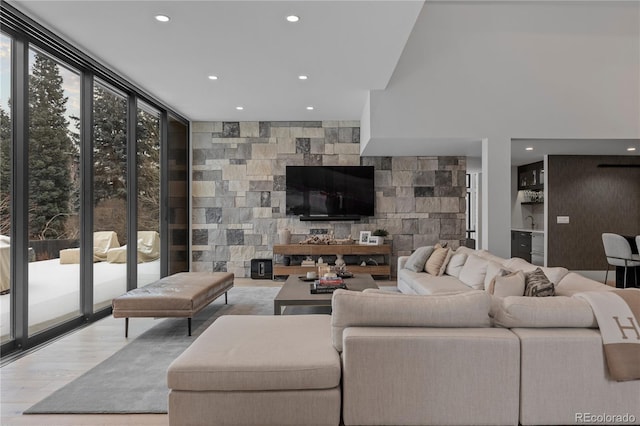 living area featuring a wall of windows, recessed lighting, and wood finished floors