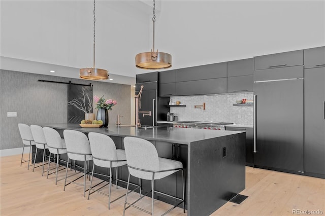 kitchen with light wood finished floors, a spacious island, a breakfast bar, decorative light fixtures, and modern cabinets