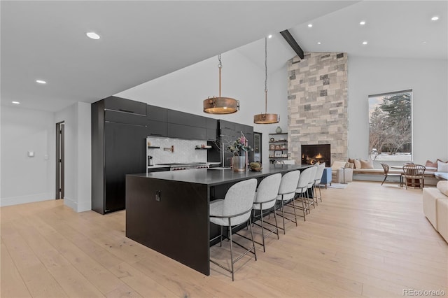 kitchen featuring light wood-style floors, a kitchen bar, dark countertops, and beamed ceiling