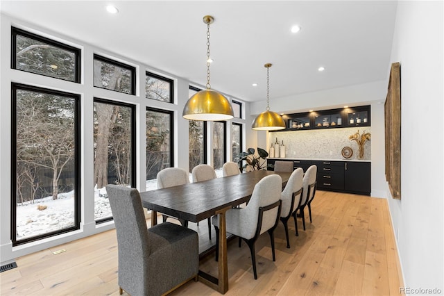 dining space with visible vents, recessed lighting, light wood-type flooring, and indoor bar