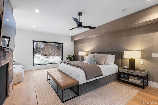 bedroom with recessed lighting, a fireplace, baseboards, and light wood finished floors