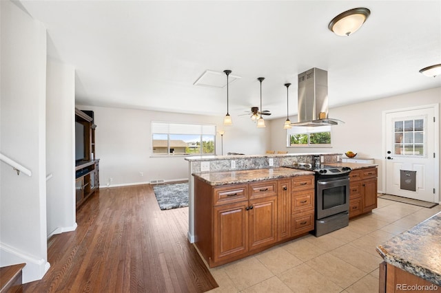16225 W 74th Dr, Arvada, CO 80007 - kitchen featuring island range hood, stainless steel range with electric cooktop, brown cabinetry, and light stone counters