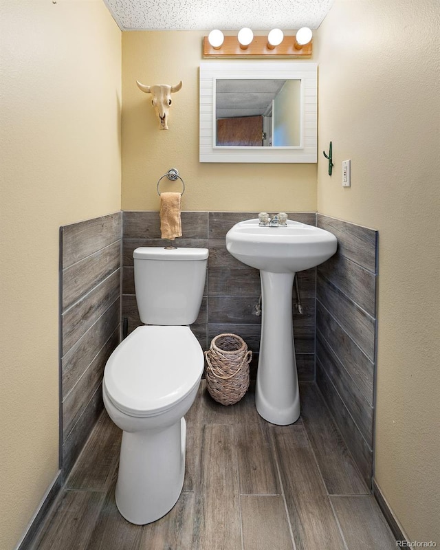 16225 W 74th Dr, Arvada, CO 80007 - half bathroom with toilet, wood finished floors, tile walls, and a wainscoted wall
