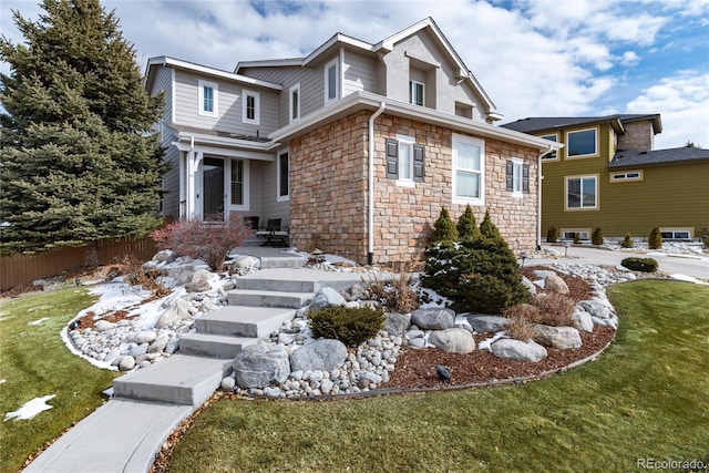 view of front of property featuring a front yard, stone siding, and fence