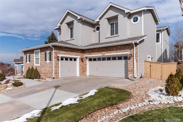 view of front of house featuring a garage, stone siding, fence, and driveway