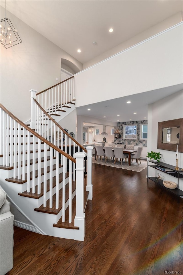 stairs with recessed lighting, wood finished floors, and a notable chandelier