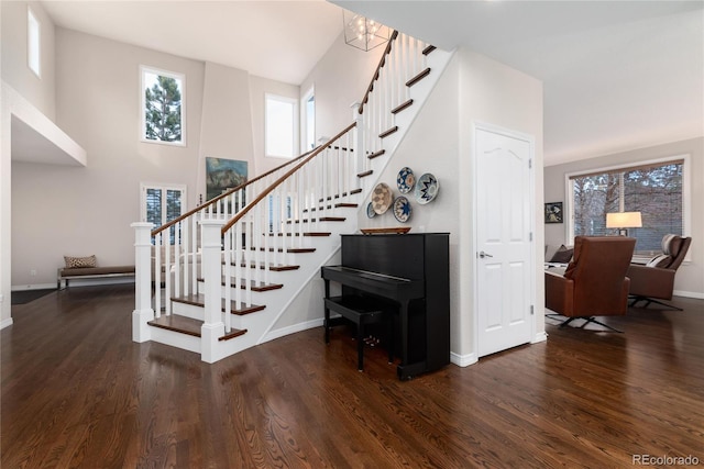 stairway with a high ceiling, baseboards, and wood finished floors