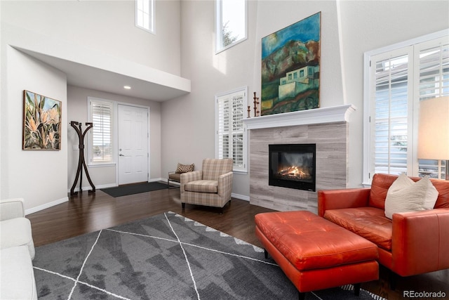 living room featuring plenty of natural light, a premium fireplace, baseboards, and dark wood-style flooring