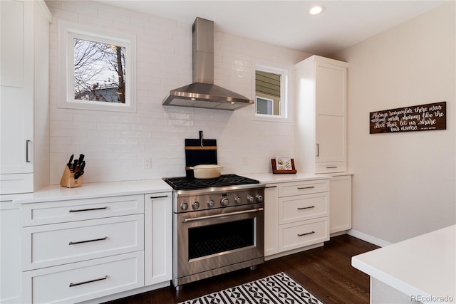 kitchen featuring wall chimney exhaust hood, light countertops, stainless steel stove, and white cabinets