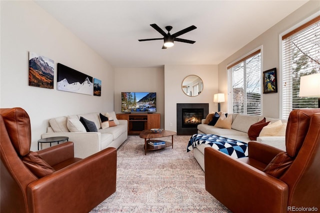 living area with ceiling fan and a glass covered fireplace