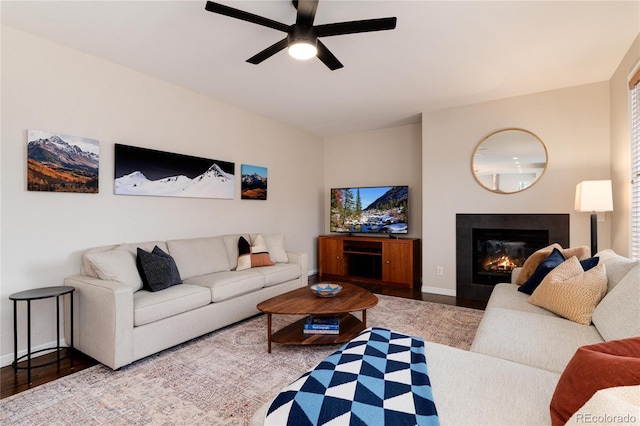 living area with ceiling fan, a fireplace, wood finished floors, and baseboards