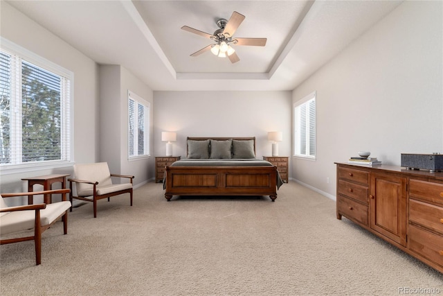 bedroom featuring baseboards, a raised ceiling, and light colored carpet