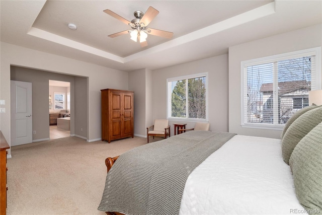 bedroom featuring a tray ceiling, light carpet, and baseboards