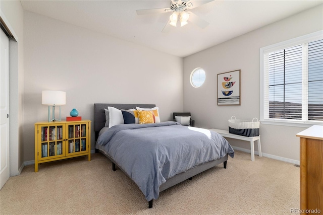 bedroom with ceiling fan, multiple windows, baseboards, and light colored carpet