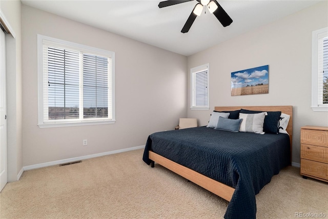 bedroom with a ceiling fan, light colored carpet, visible vents, and baseboards