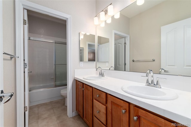 bathroom featuring tile patterned flooring, enclosed tub / shower combo, a sink, and double vanity