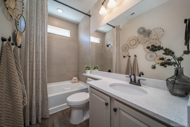 full bathroom with wood-type flooring, toilet, shower / bath combo with shower curtain, and vanity