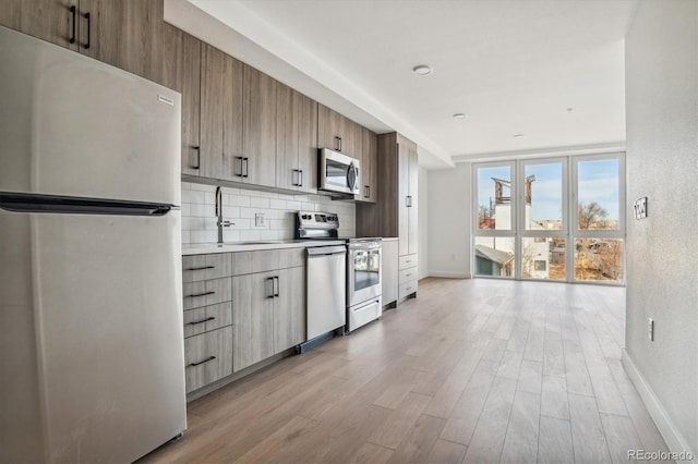 kitchen with light hardwood / wood-style flooring, stainless steel appliances, sink, and tasteful backsplash